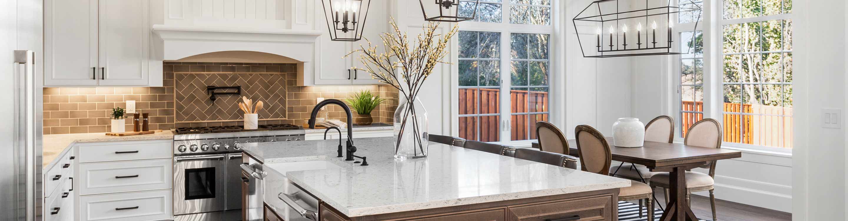 dark wood flooring in kitchen with large island with white stone countertops and white cabinets with brown subway tile backlspash